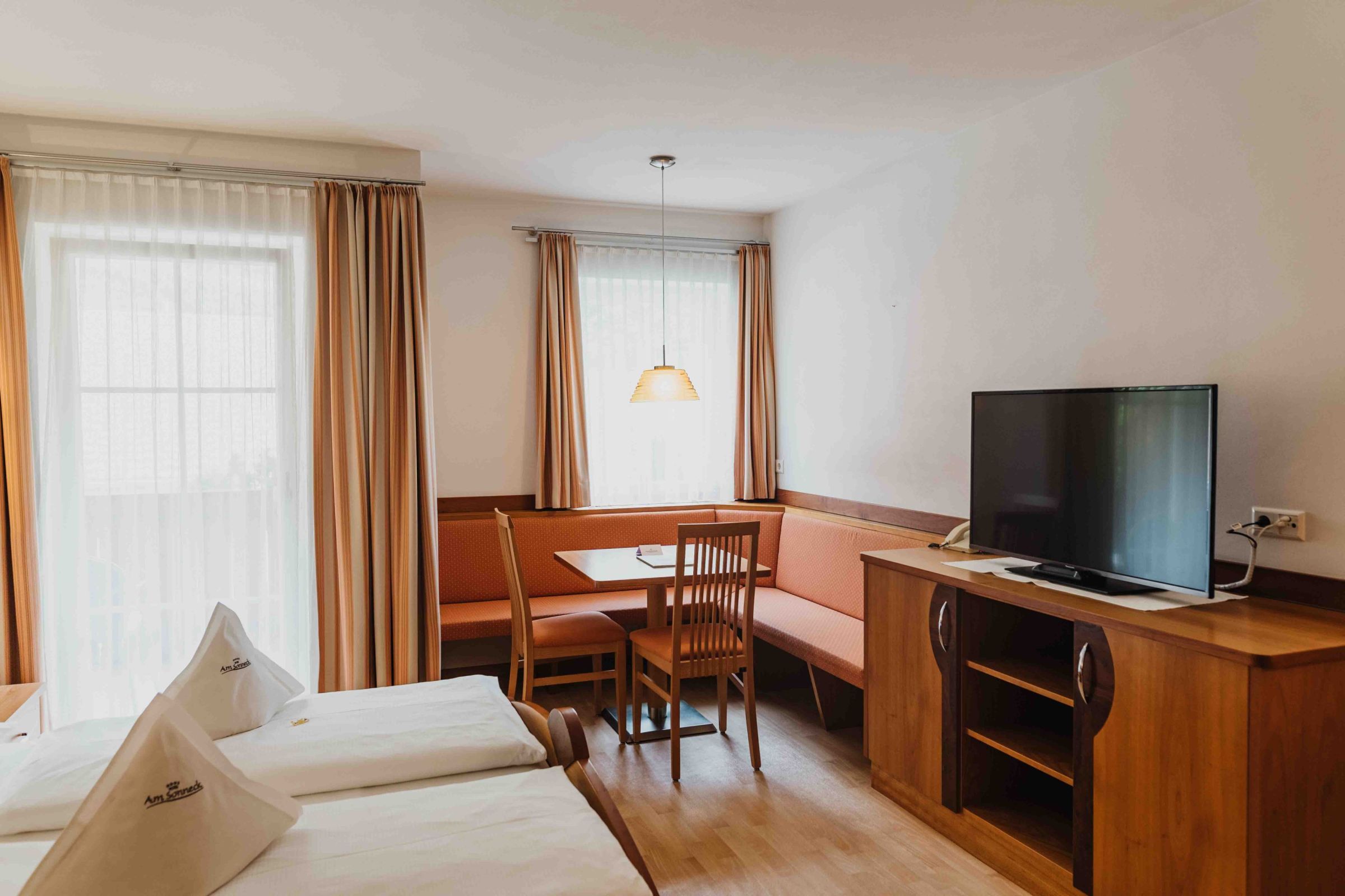 Gemütliche Sitzecke mit TV im Doppelzimmer Rosenduft – Hotel Am Sonneck